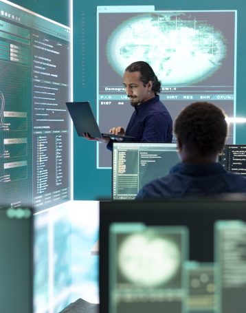 Professional hacker using ransomware and phishing tactics to compromise networks Professional hacker using ransomware and phishing tactics to compromise networks and gather intelligence for national security during cyberwarfare. Governmental spyware on big screen.